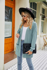 Air Force Blue cable-knit cardigan with pockets and open front, styled with jeans.