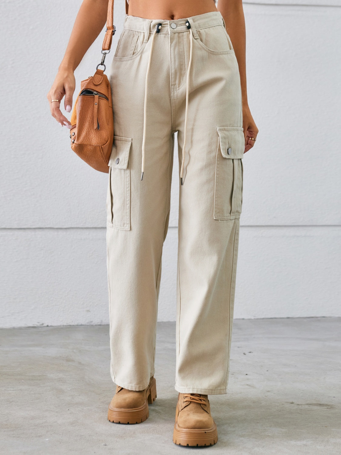 Tan denim cargo pants with drawstring waist and wide legs.