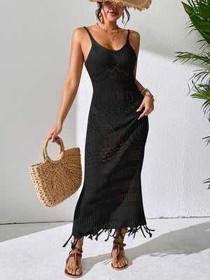 Black crochet maxi dress with fringe hem and V-neck, styled with sandals and straw bag.