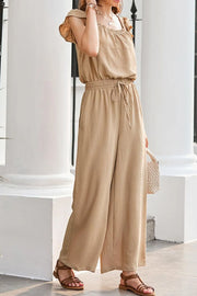 Tan textured ruffle-sleeve drawstring palazzo jumpsuit with wide legs and elastic waist.