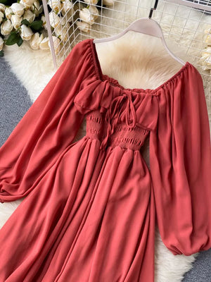 Maternity dress in watermelon red with square neckline, ruffled detail, tie front, smocked waist, and balloon sleeves.