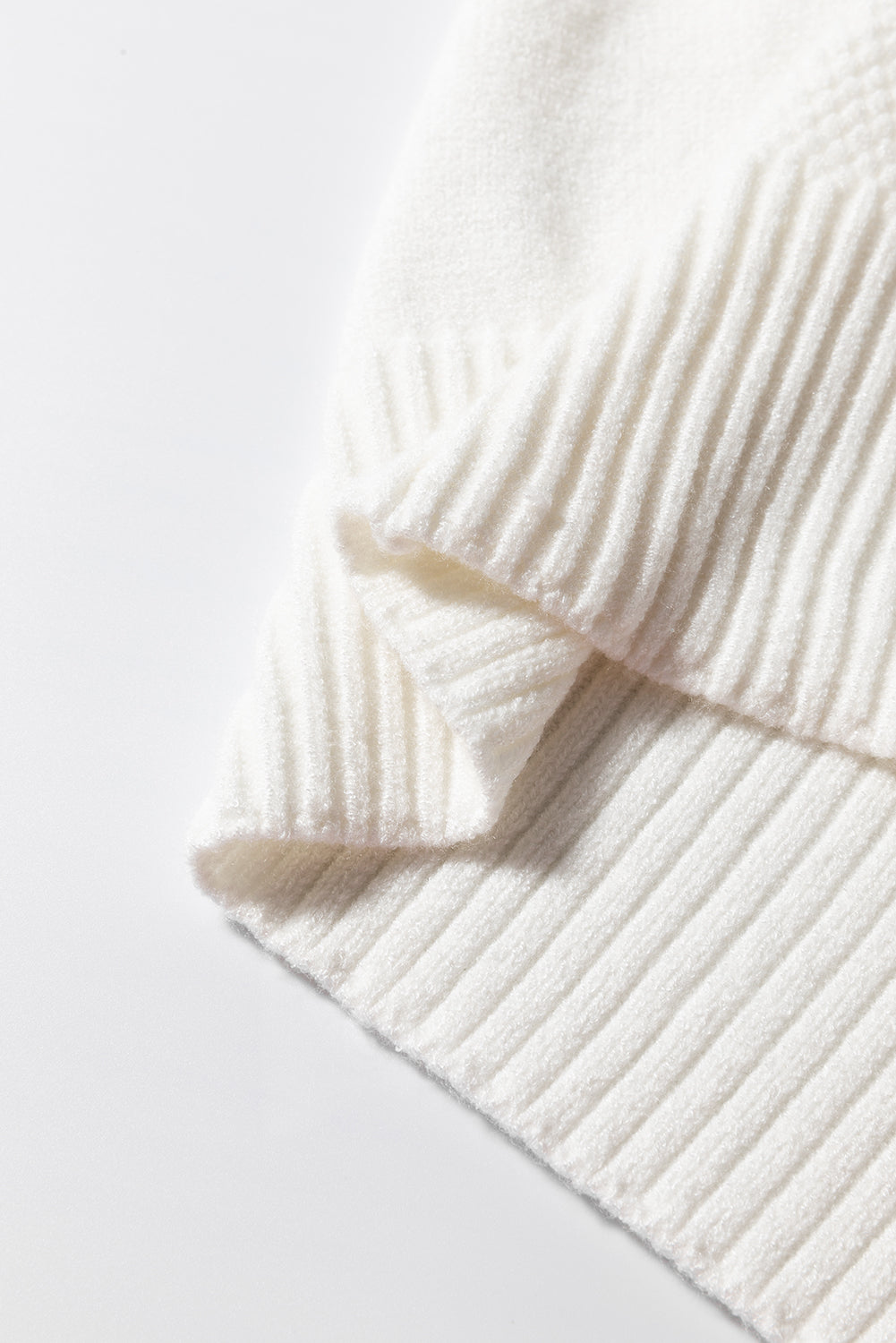 Diamond cable knit sweater in white with ribbed texture and folded detail.