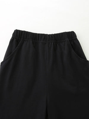 Black cotton baby shorts with elastic waistband and pockets.