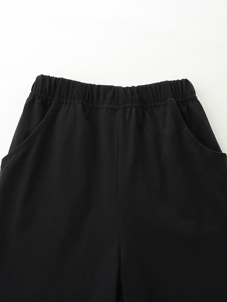 Black cotton baby shorts with elastic waistband and pockets.