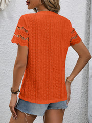Orange eyelet blouse with scalloped short sleeves and textured pattern.