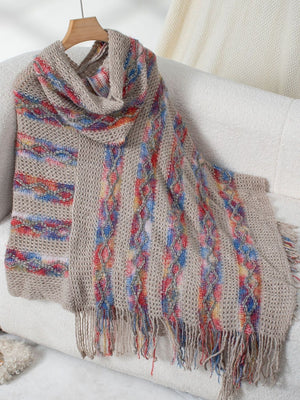 Textured knit hooded cape in beige with colorful striped and cable knit details and fringe.