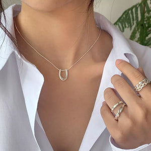 Sterling silver U-shaped pendant necklace on a delicate chain, styled with rings