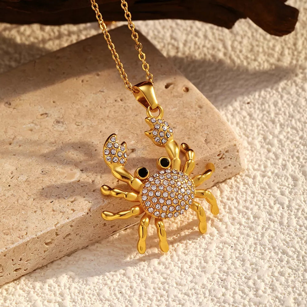 Gold-plated crab pendant necklace with crystal accents and black eyes on a delicate chain.