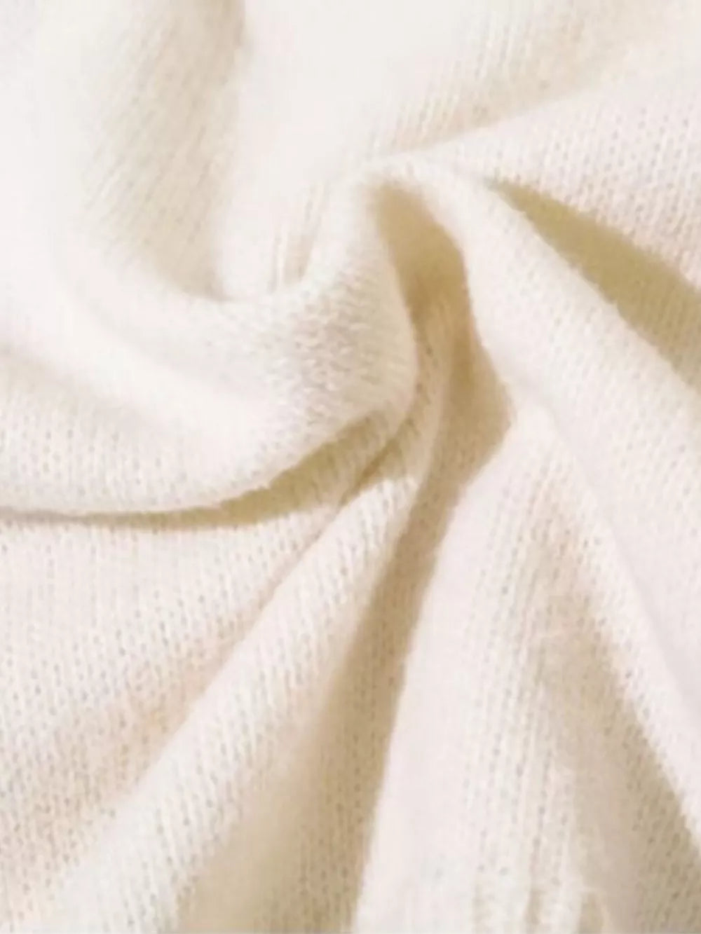 Cream knit sweater with textured details and abstract pattern.