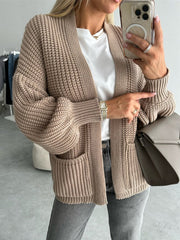 Beige textured puff sleeve cardigan with pockets and ribbed cuffs.