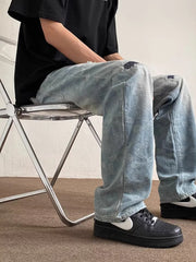 Men's light wash distressed wide-leg jeans with paisley pattern and ripped knees.
