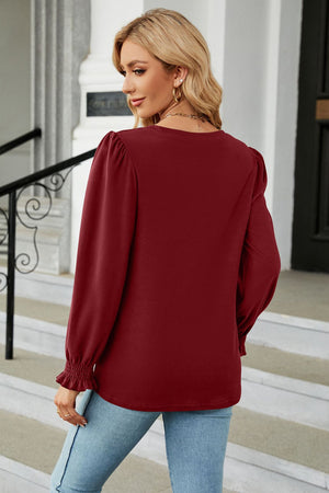 Burgundy smocked cuff puff sleeve blouse with a crew neck, styled with jeans.