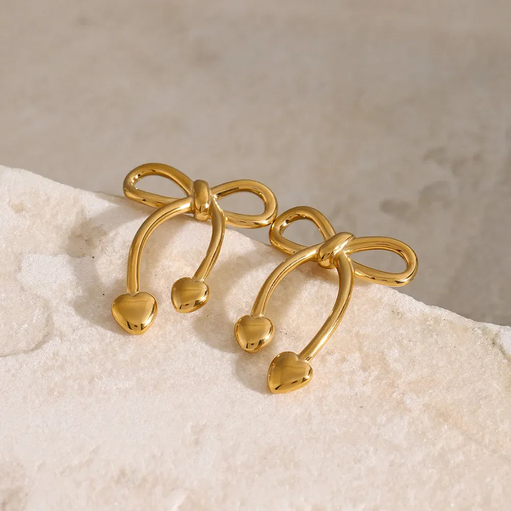 Gold heart-tipped bow drop earrings with delicate curves.