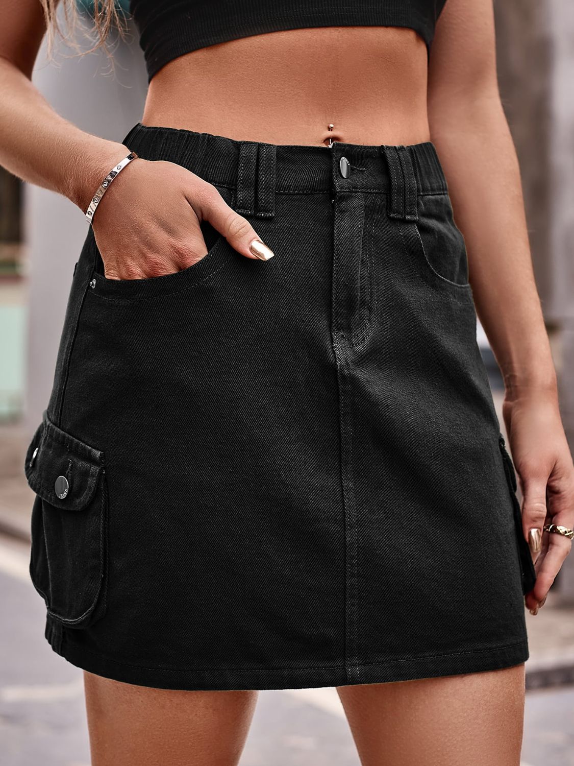 Black denim utility mini skirt with cargo pockets and elastic waistband.