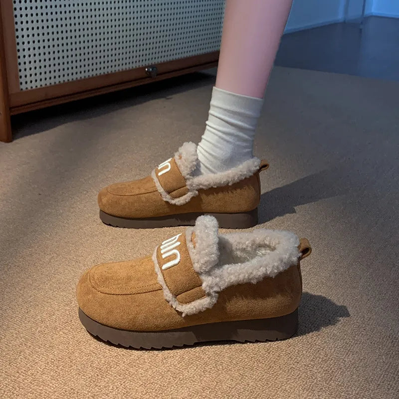 Caramel shearling loafers with logo strap detail and white socks.