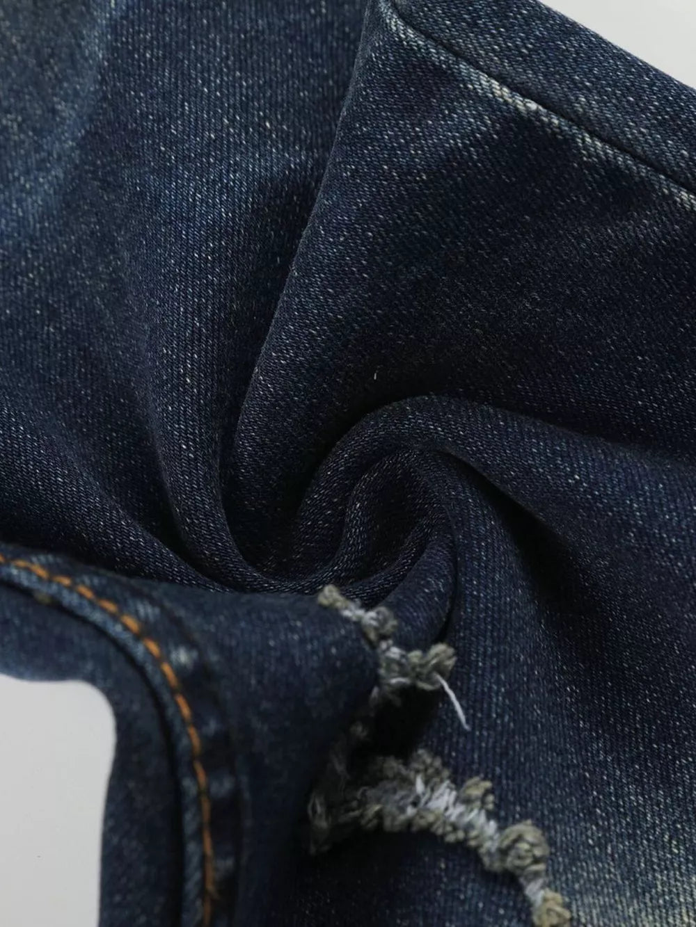 Distressed dark wash flare jeans in blue cotton with frayed hem detail.