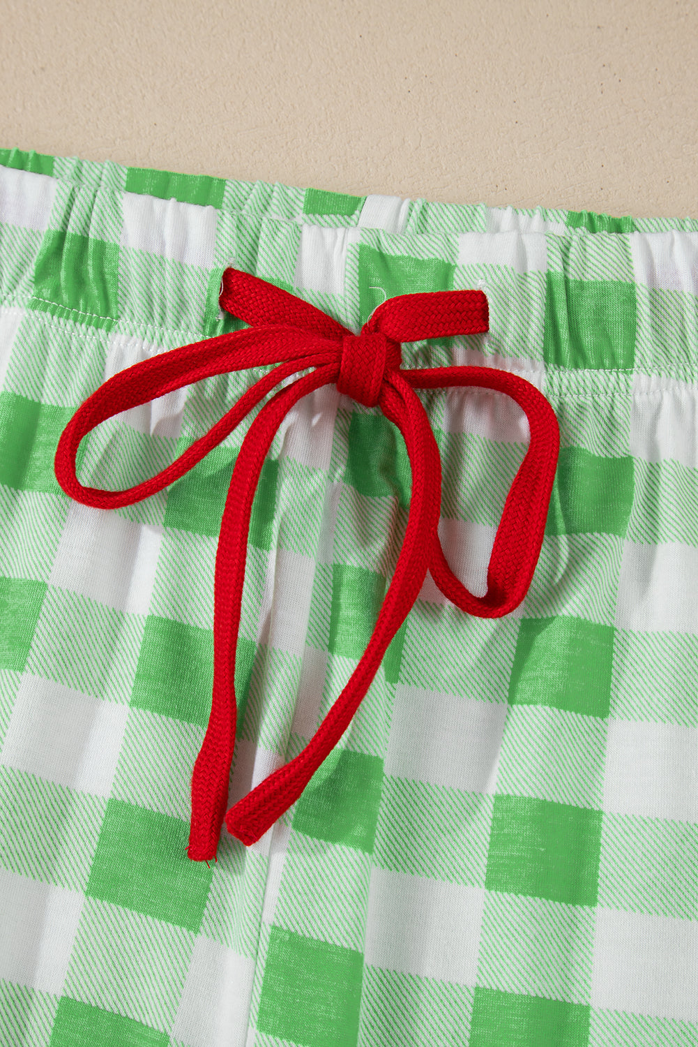 Festive gingham pajama shorts in light green with white checks and a red drawstring bow.