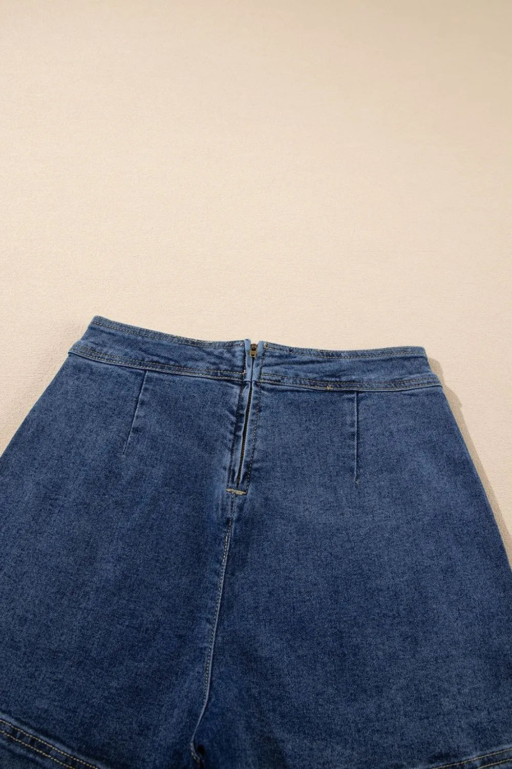 Denim wrap skort in medium wash with zipper closure and patch pockets.