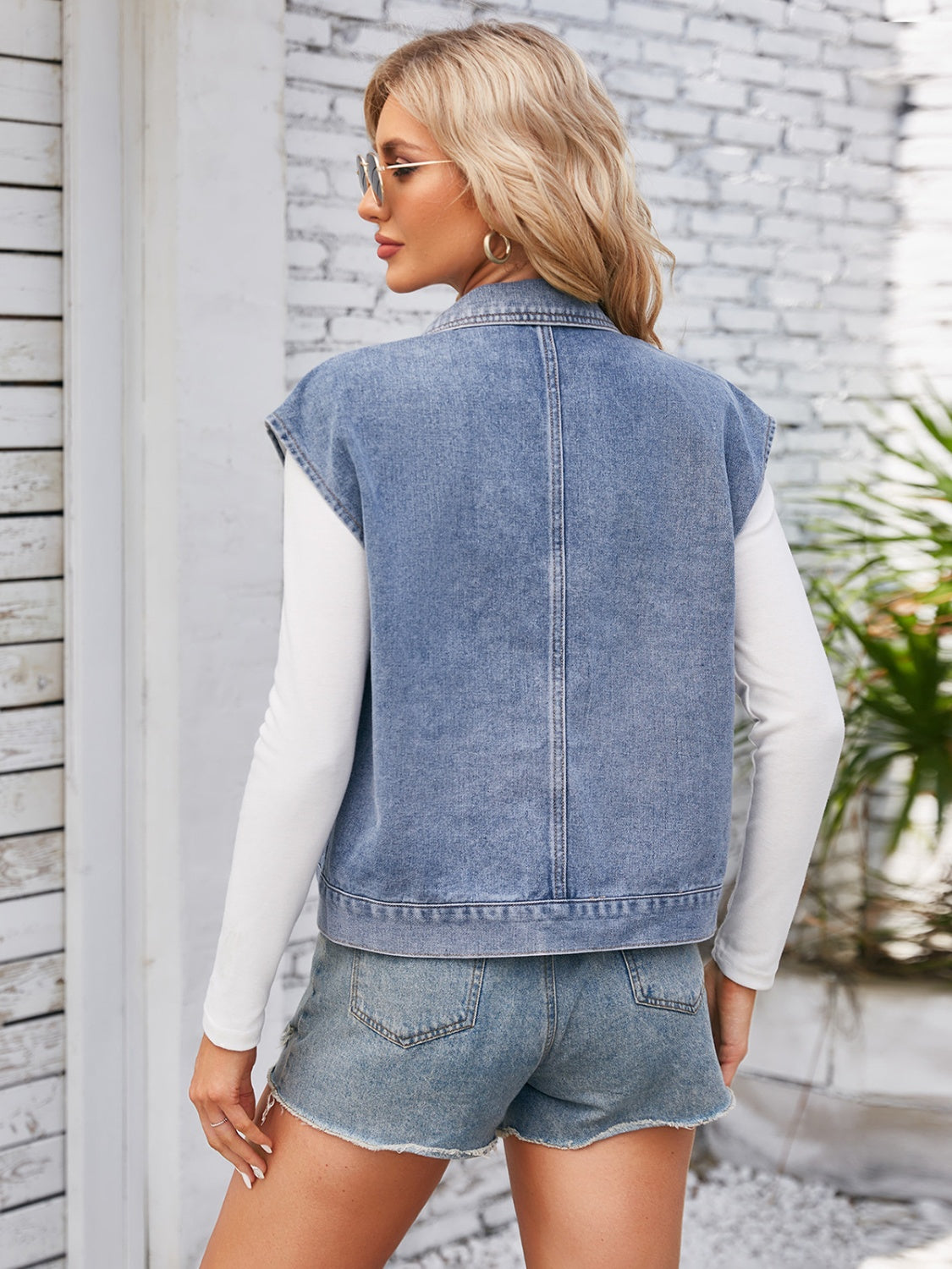Sleeveless washed denim utility jacket in dusty blue with buttoned front detail.