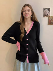 Black ribbed cardigan with pink contrast trim and buttons, featuring pink arm warmers.