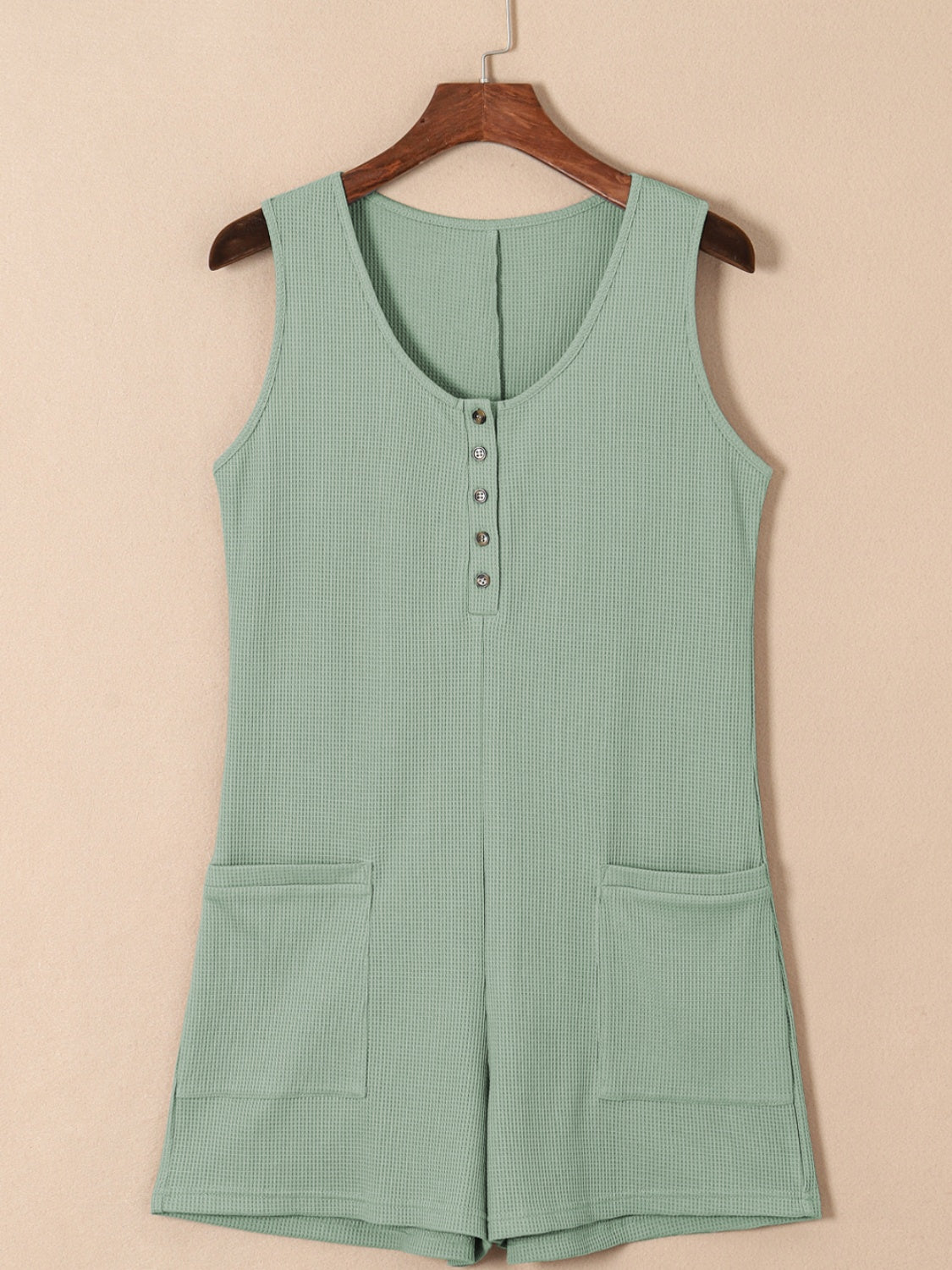 Sage green waffle knit button-down romper with pockets and a scoop neckline.