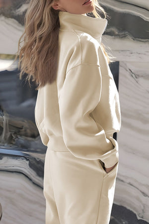 Beige quarter-zip sweatshirt with high collar and jogger pants with pockets.