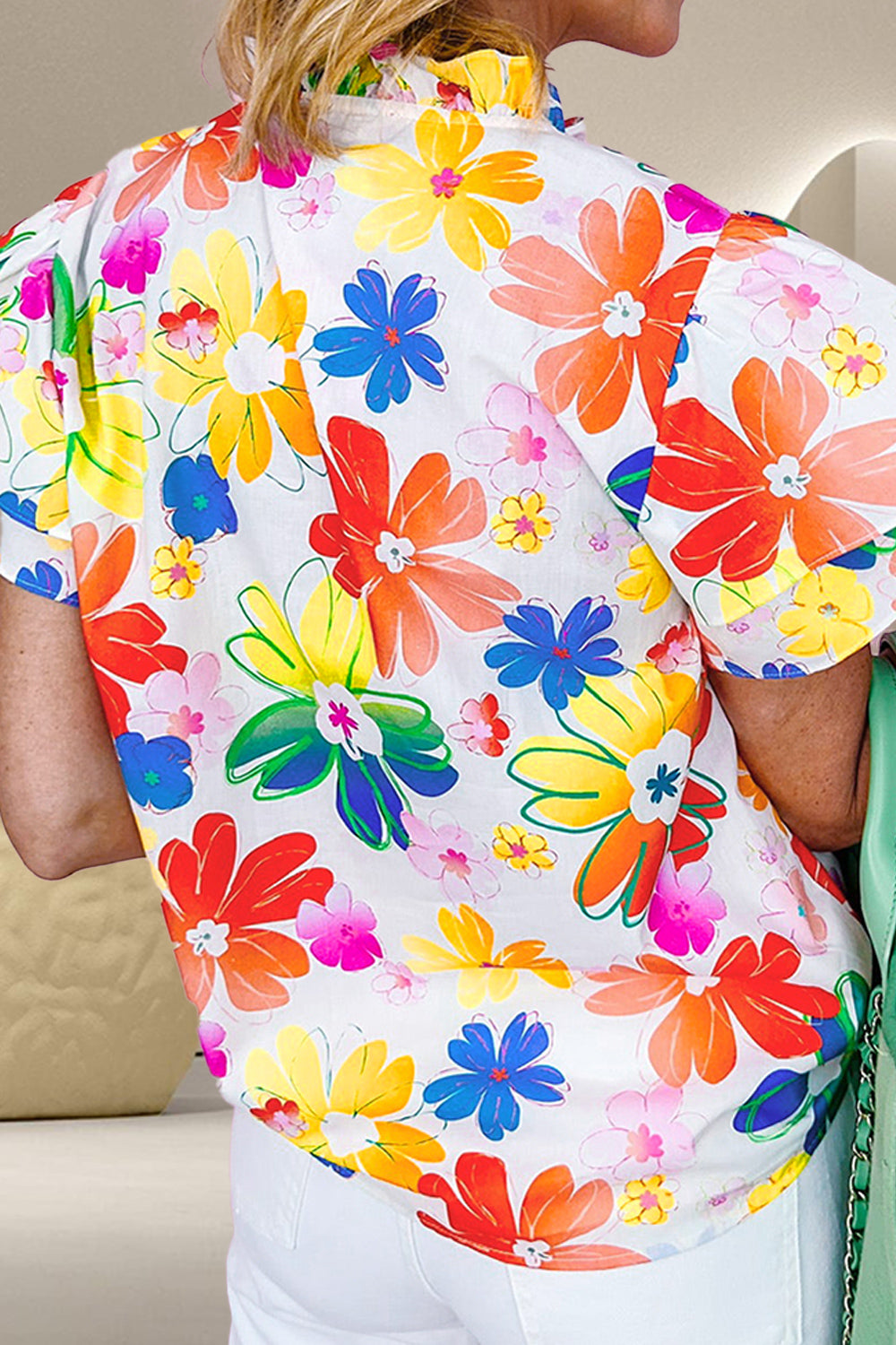 Vibrant floral print blouse with ruffle collar and short sleeves.