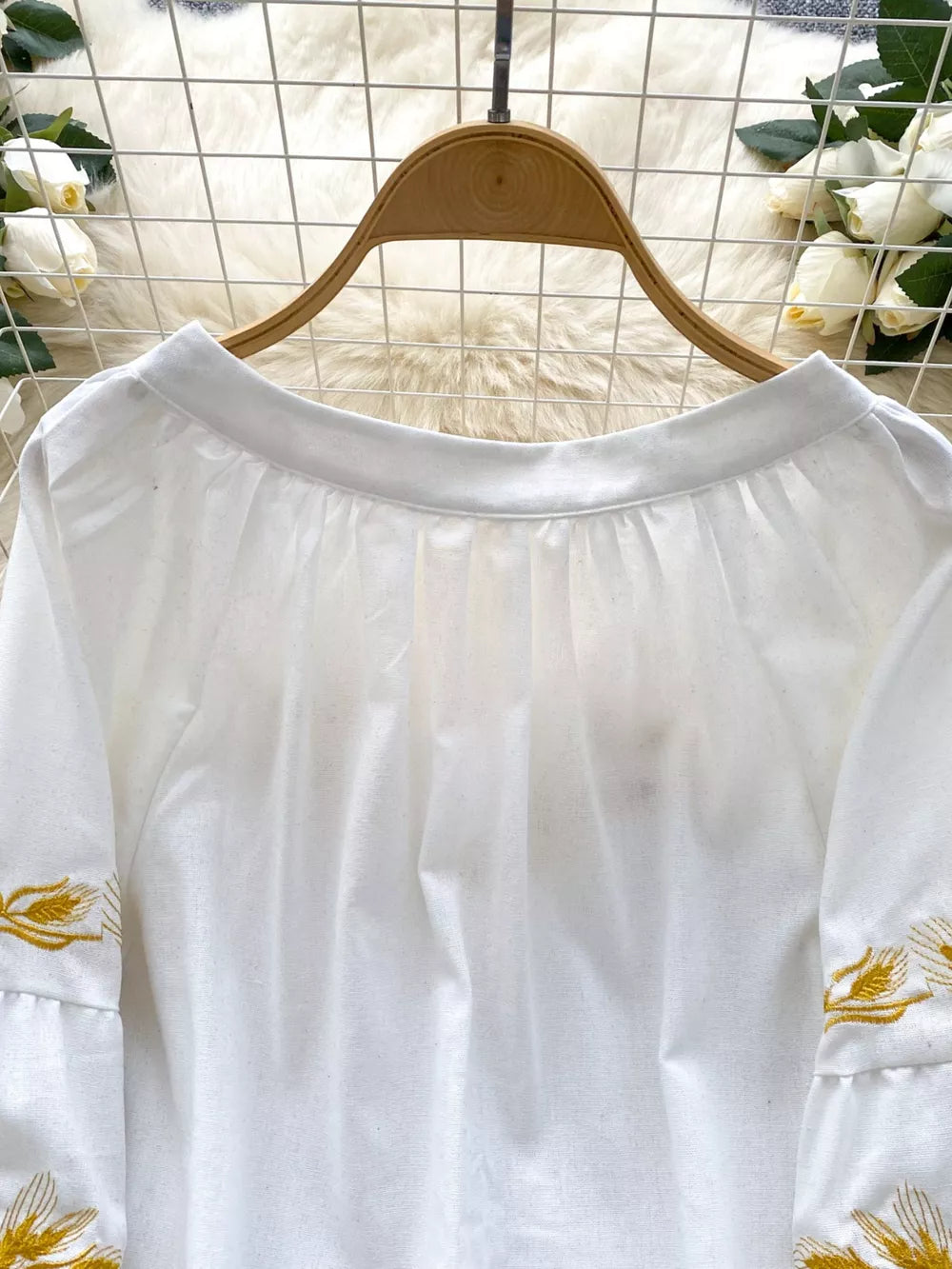 White embroidered tie-neck folk blouse with ruffled sleeves.