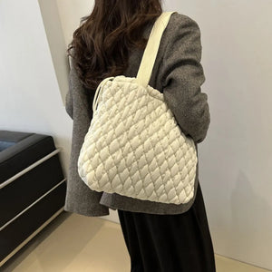 Ivory quilted drawstring carryall bag with diamond pattern and single strap.