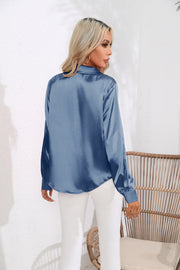 Glossy satin button-down blouse in light blue, shown from the back.