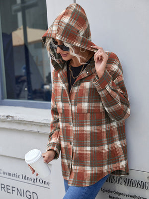 Brown plaid hooded shacket with relaxed fit and buttoned front, styled casually.