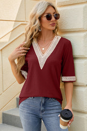 Burgundy textured v-neck blouse with lace trim on neckline and sleeves.