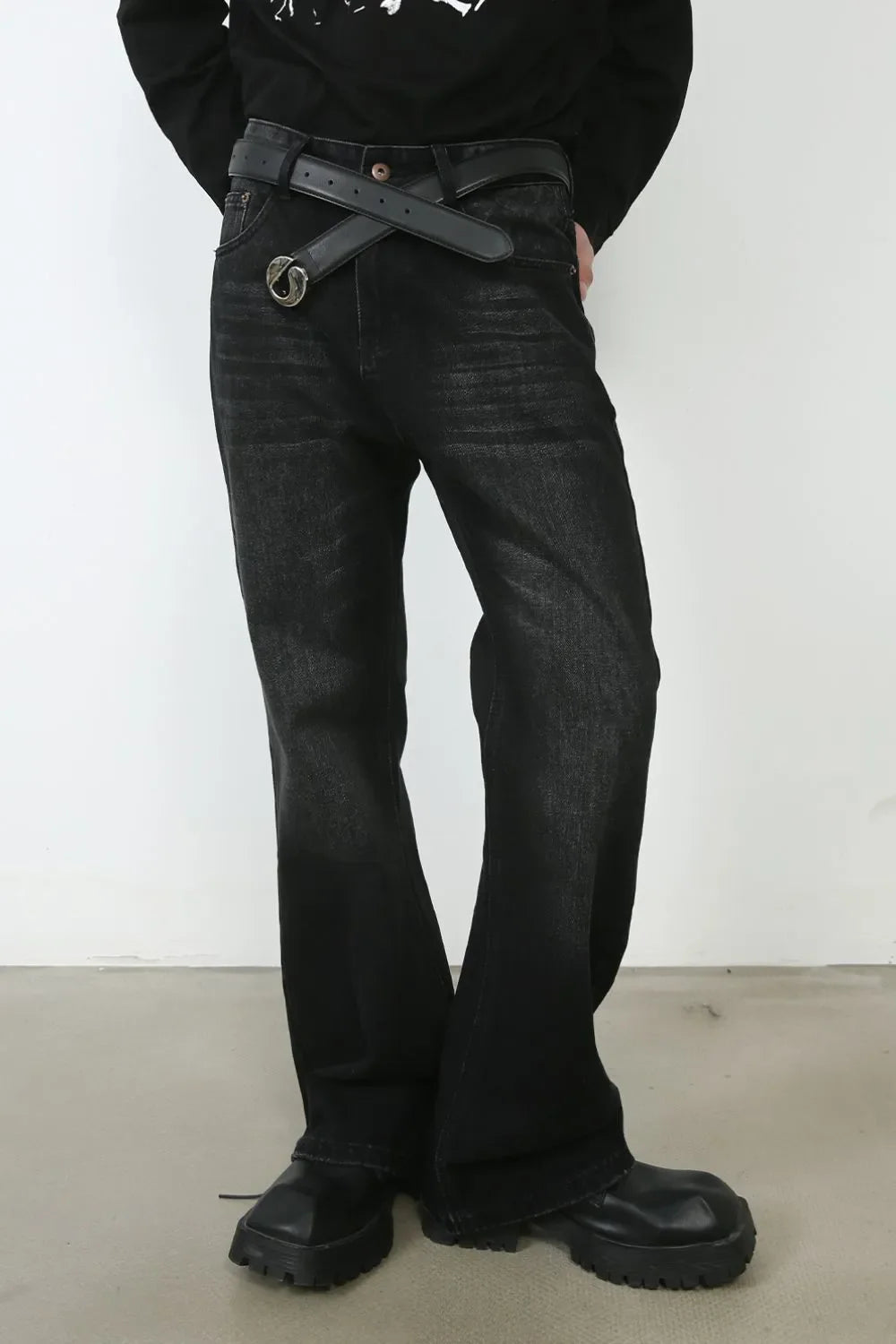 Faded black denim flare jeans with a distressed wash and a black belt.