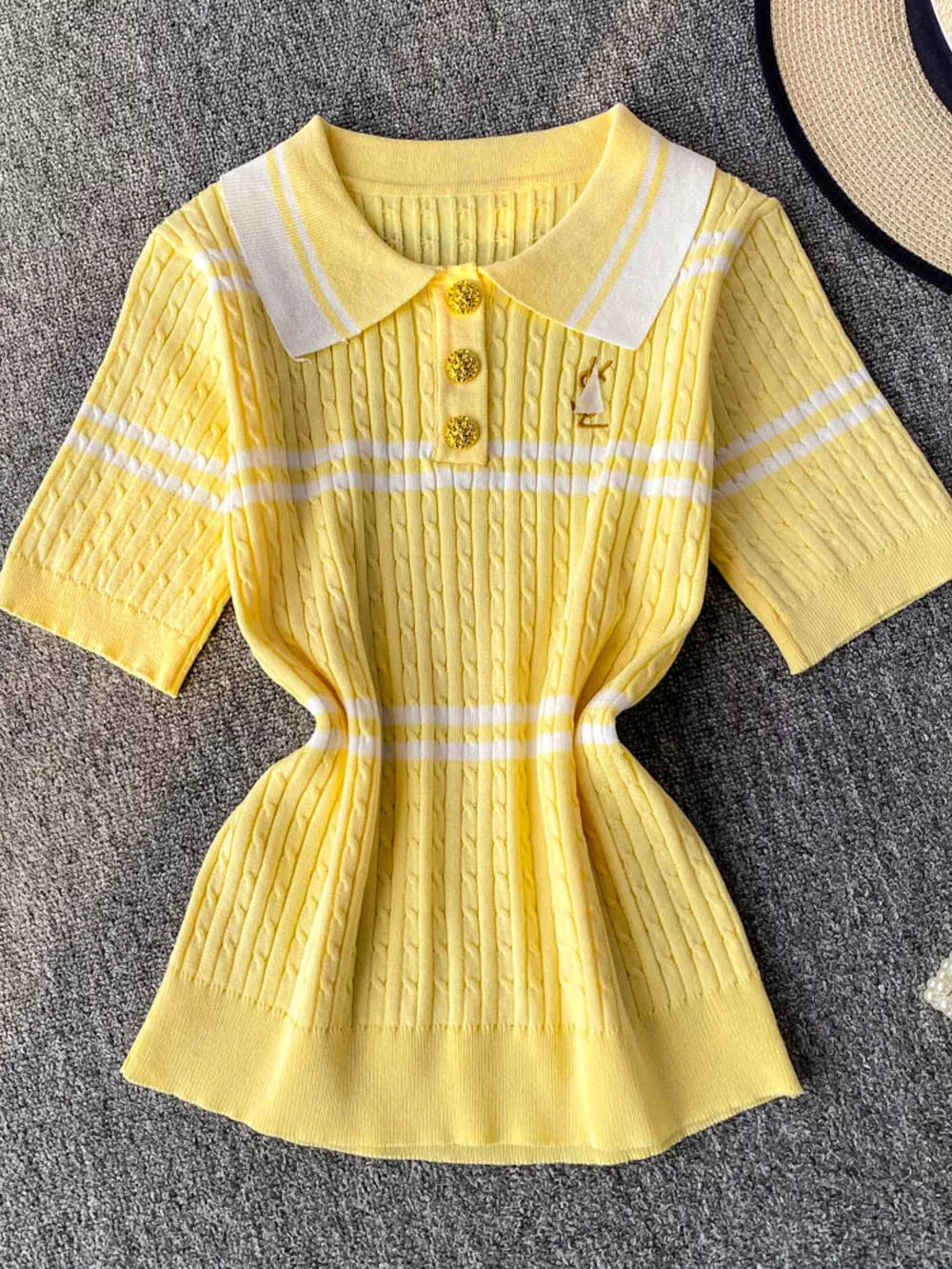 Yellow cable knit polo shirt with white stripes, buttoned placket, and decorative pin.