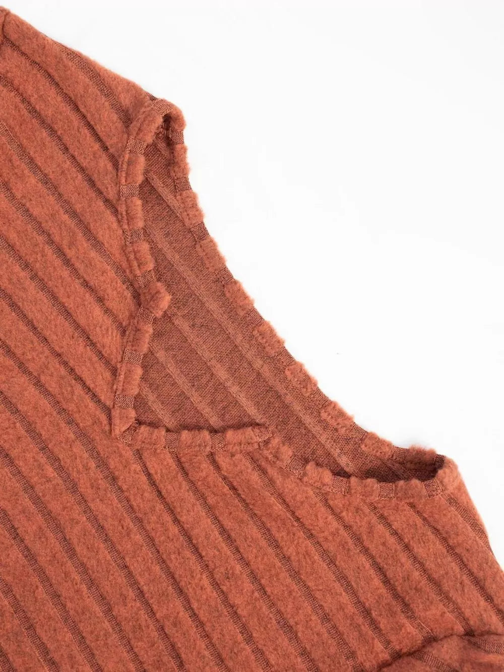 Ribbed knit A-line dress in rust with a V-neck and raw edge detail.