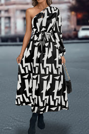 Black and white geometric print asymmetric maxi dress with belt and one long sleeve.