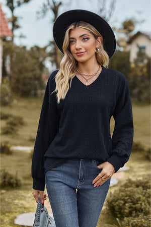 Dark blue textured cable knit v-neck sweater with long sleeves.