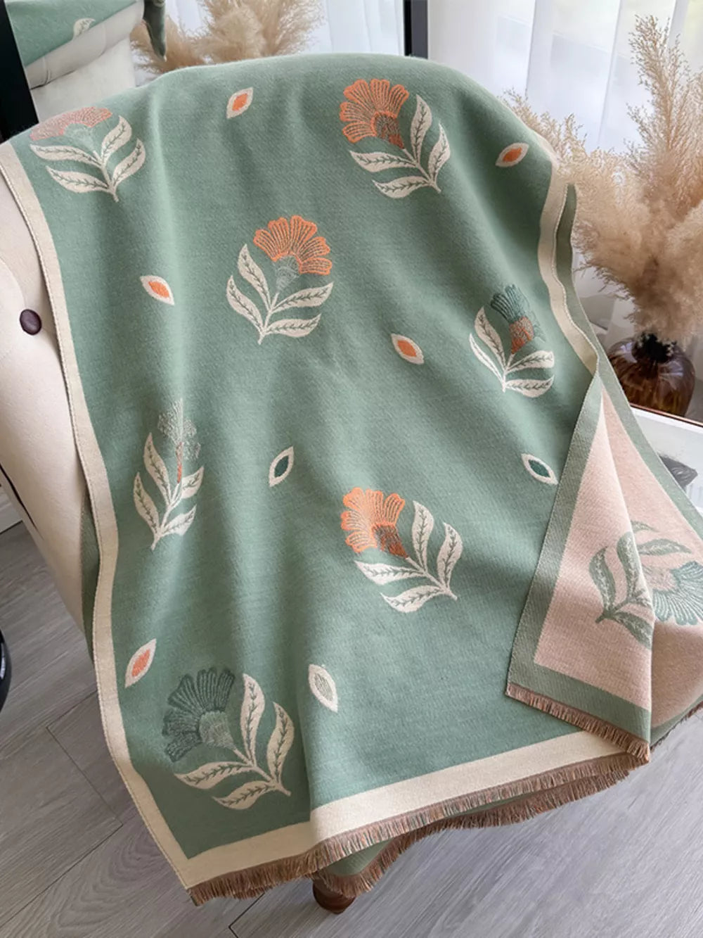 Green floral print fringed shawl with beige trim and tassels.