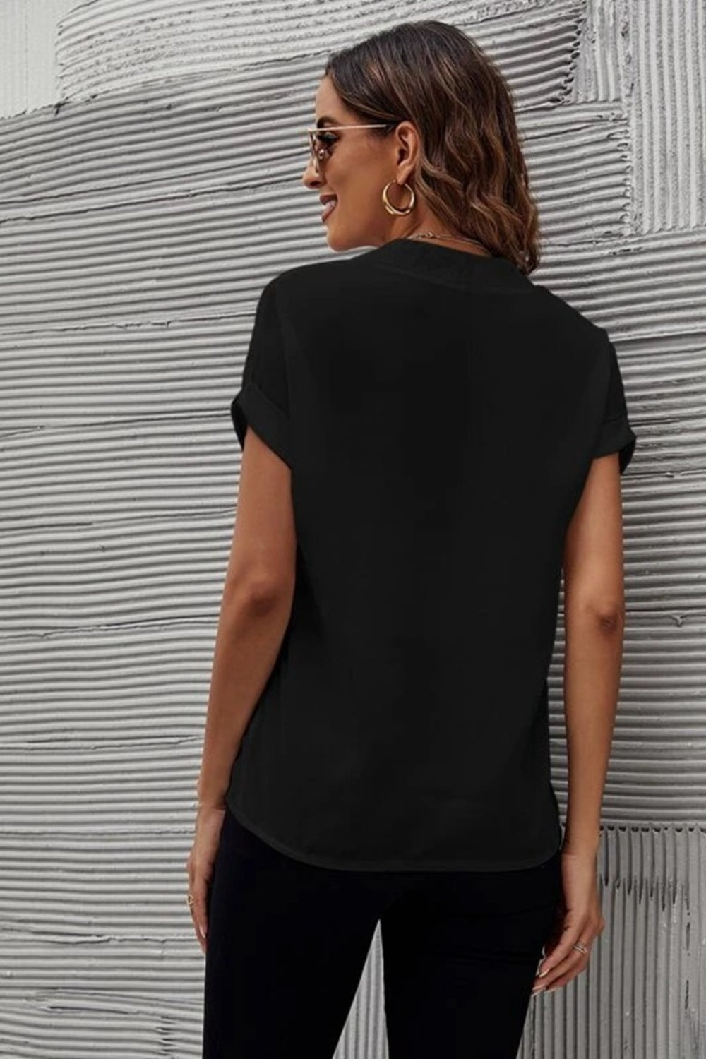 Black cuffed sleeve blouse with a plunge front, shown from the back.