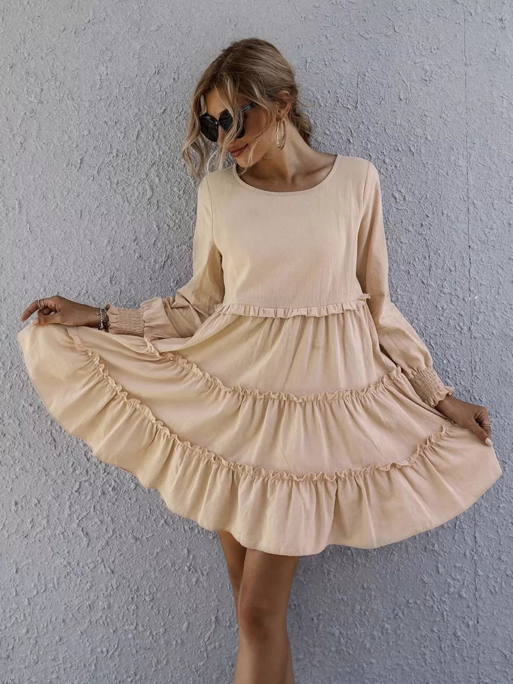Apricot ruffled mini dress with long sleeves and tiered skirt.
