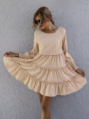 Apricot ruffled mini dress with long sleeves and tiered skirt.