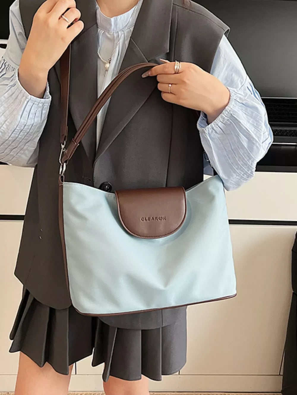 Chic canvas hobo crossbody bag in blue with brown trim and flap detail.