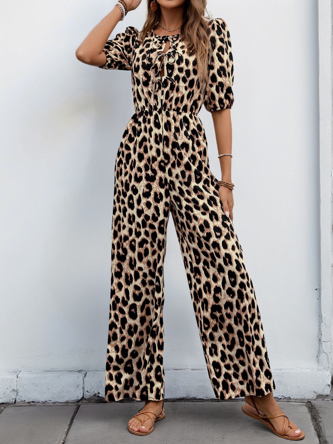 Leopard print jumpsuit with puff sleeves and tie-neck detail.