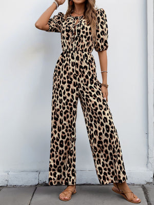 Leopard print jumpsuit with puff sleeves and tie-neck detail.