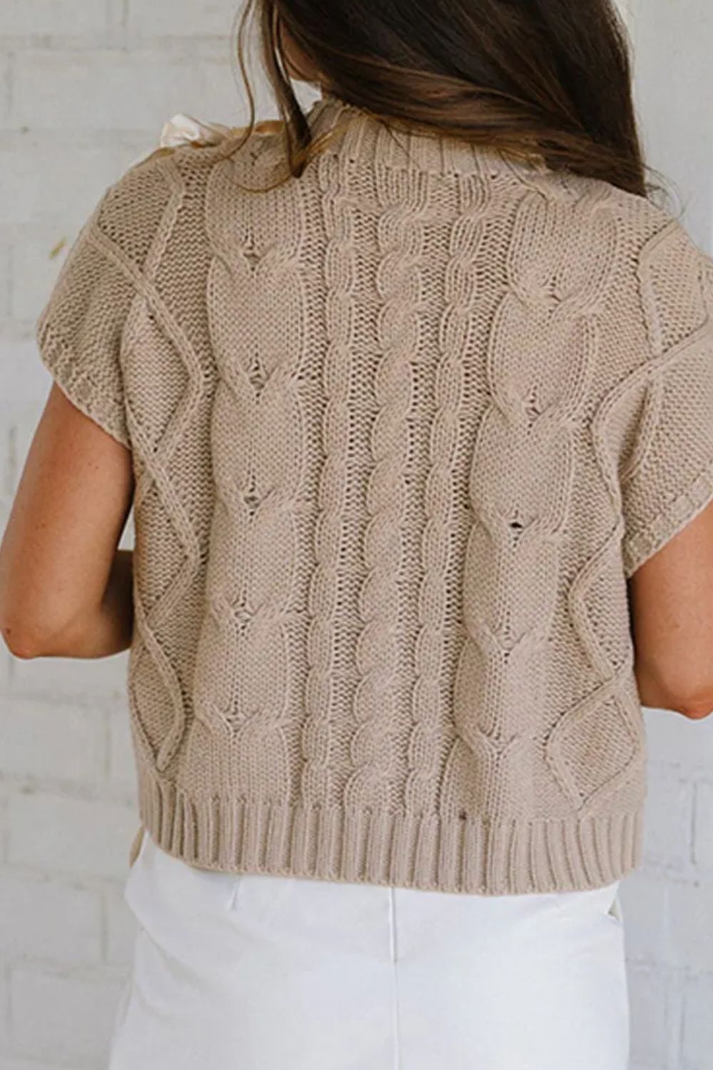 Mocha cable knit mock neck sweater with short sleeves and bow detail on shoulder.