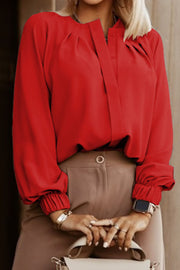 Red pleated yoke blouse with button detail and elastic cuffs.