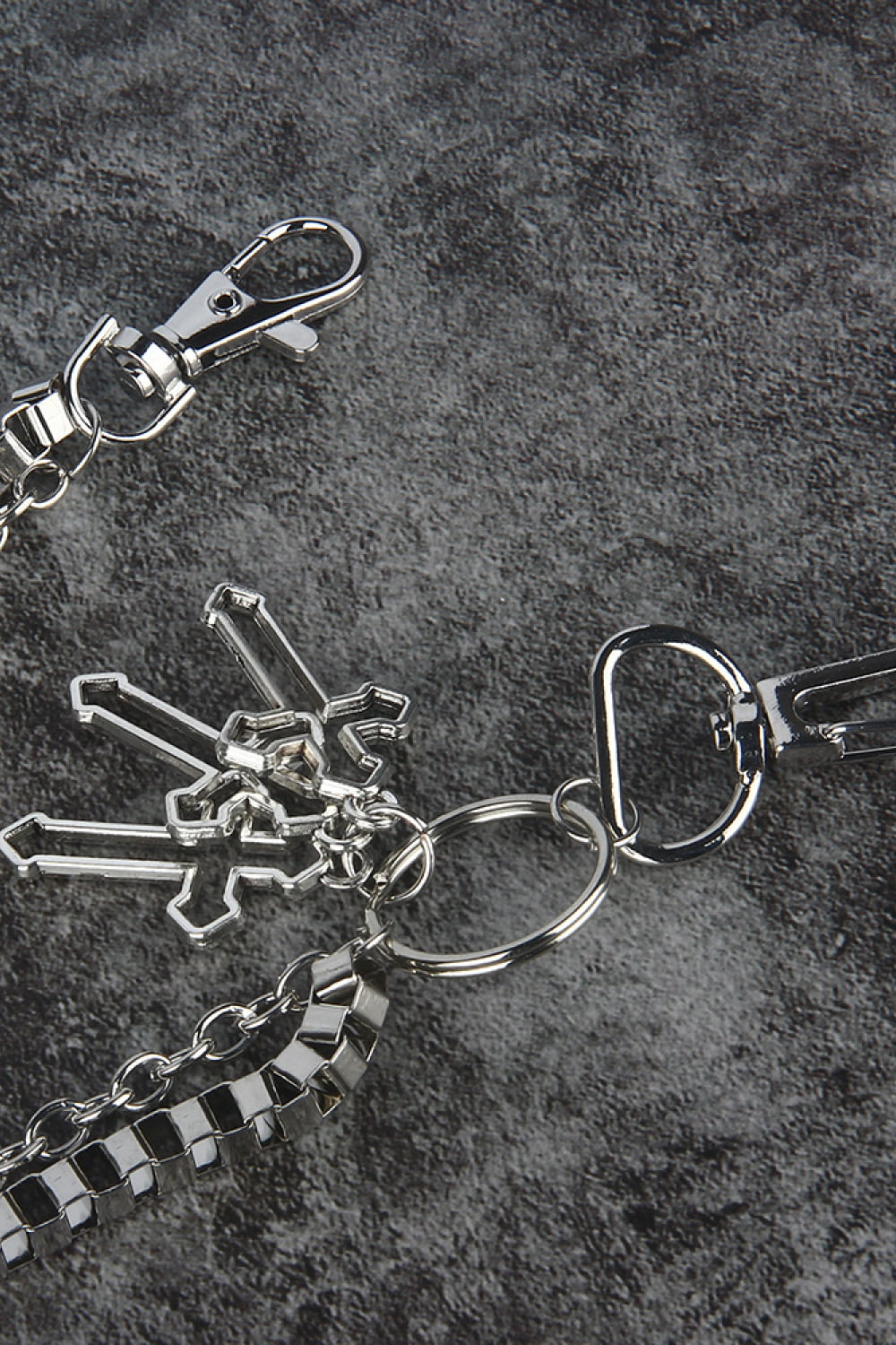 Silver geometric chain waist accessory with crossed charms and lobster clasps.