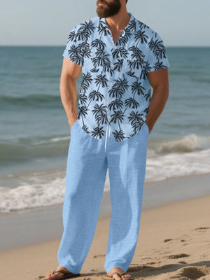 Men's pastel blue relaxed fit pants with drawstring waist, paired with a tropical palm print short sleeve button-down shirt.