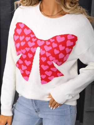 White knit sweater with a large red and pink heart bow graphic, round neck, long sleeves.