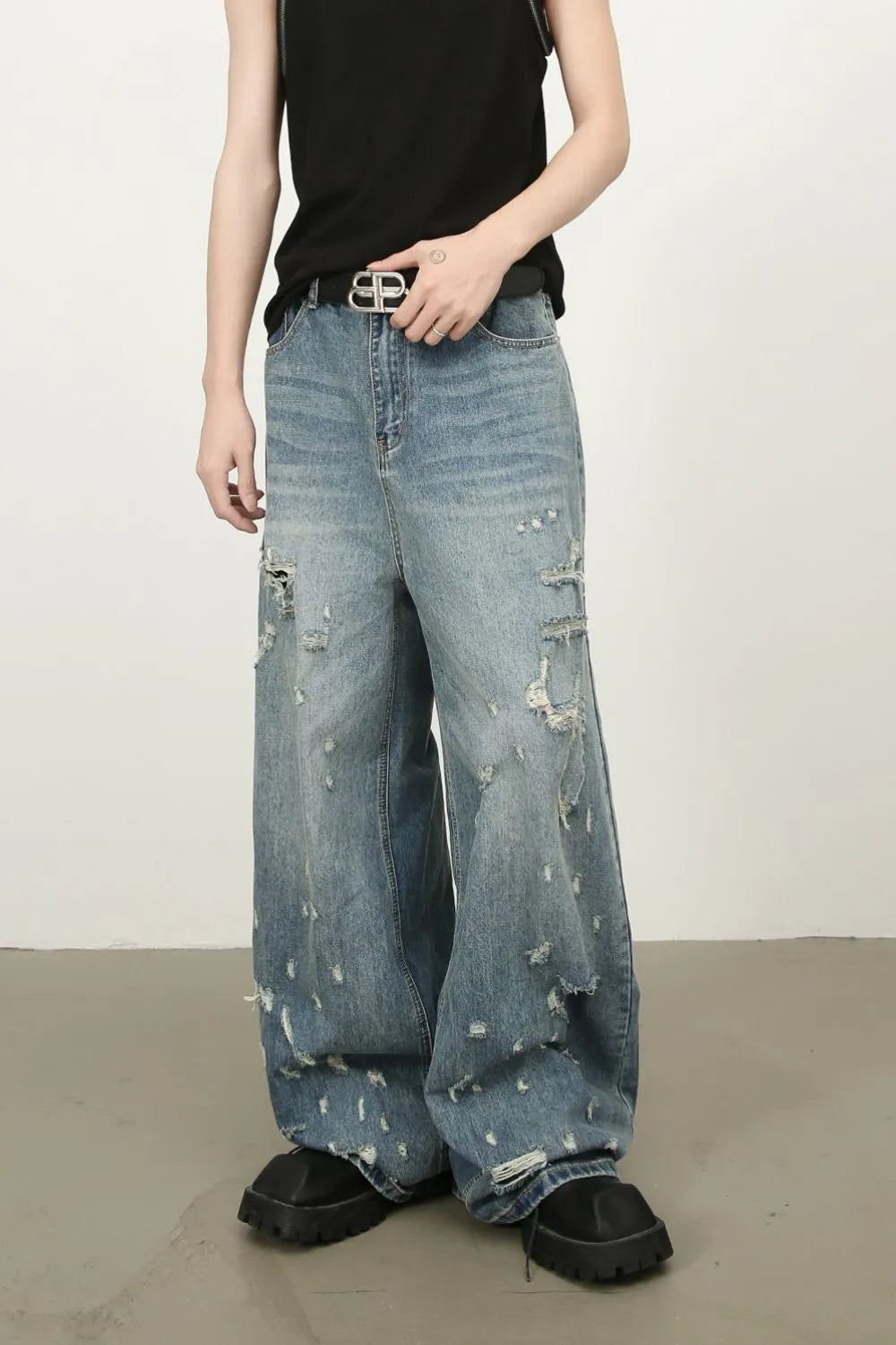 Distressed palazzo jeans in medium wash denim with raw edge detail and ripped accents.